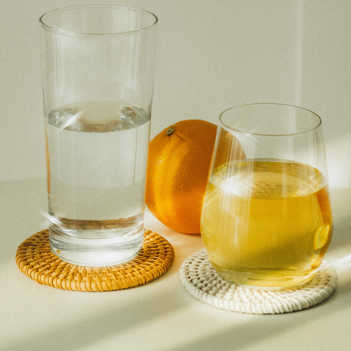 Two-glasses-placed-on-brown-and-white-woven-coasters-emphasizing-the-coasters'-functionality-with-a-simple-design