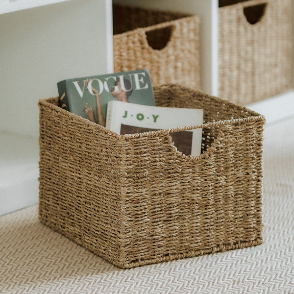 Cube seagrass woven storage basket set of 3, one filled with books inside placed near a white shelf