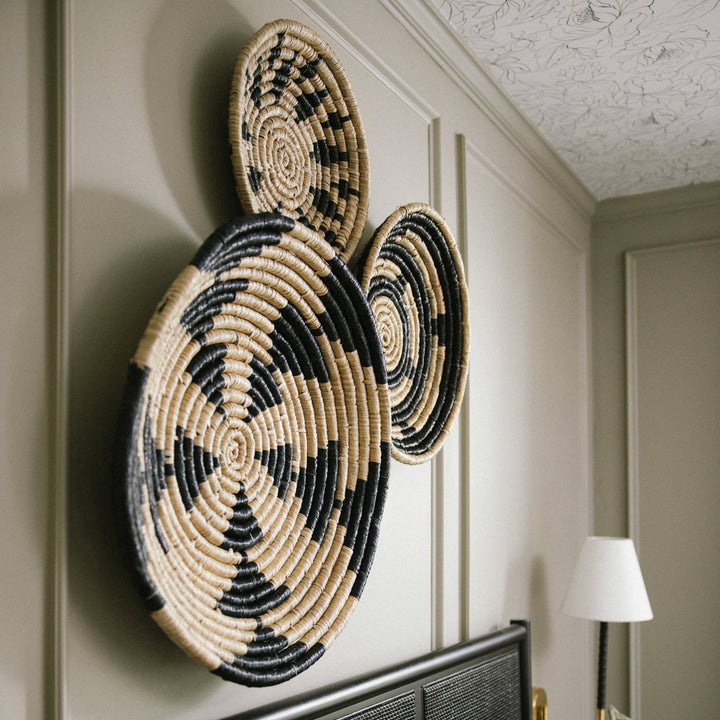 Intricate-geometric-seagrass-woven-black-and-beige-wall-basket-decor-near-a-tree