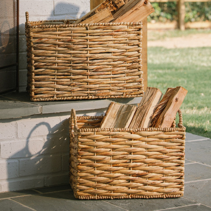 Two rectangle water hyacinth wicker baskets filled with wood outside