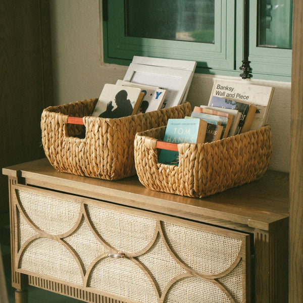 Two rectangle arrow water hyacinth wicker storage basket filled with books on a wooden table