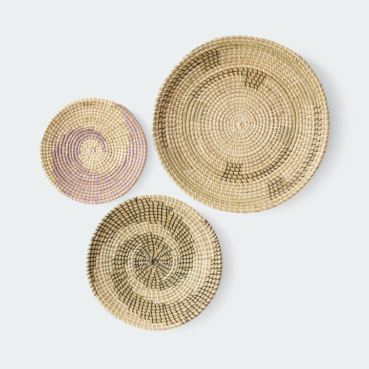 Set of three round woven wall baskets in natural, brown, and purple colors with hanging rope by Artera Home