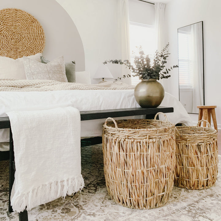 A cozy bedroom with two cylindrical wicker storage baskets placed by the bed