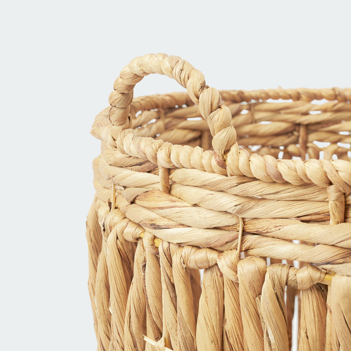 A close-up of the thick, twisted handle on a cylindrical wicker storage basket