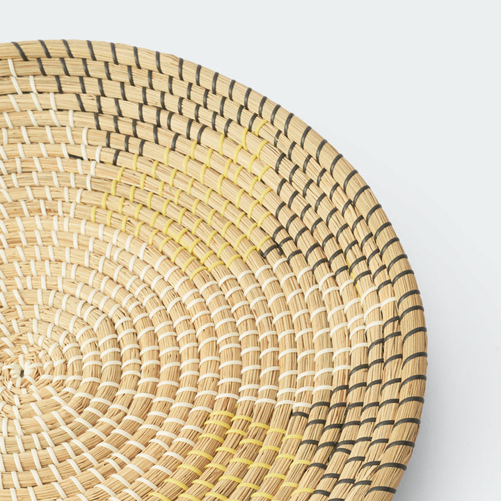 Three round, shallow wicker wall art in varying sizes and colors, including natural beige and light peach