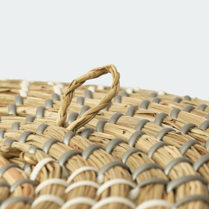 A close-up look of a round seagrass wall basket decor with a floral pattern