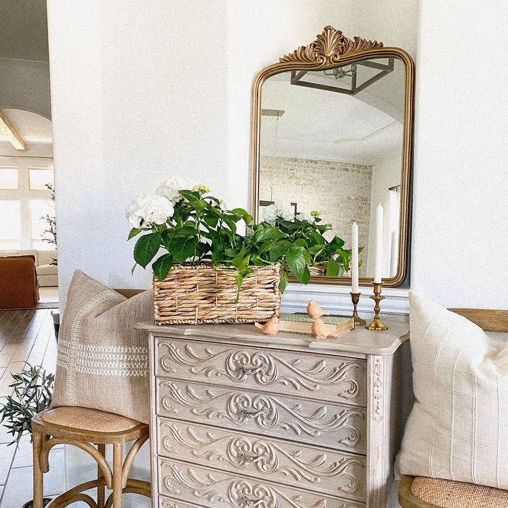 A rectangular twisted water hyacinth wicker storage basket with built-in handles leans to the left side