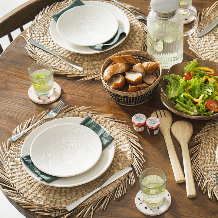 Round sunburst seagrass woven placemat with a white plate above