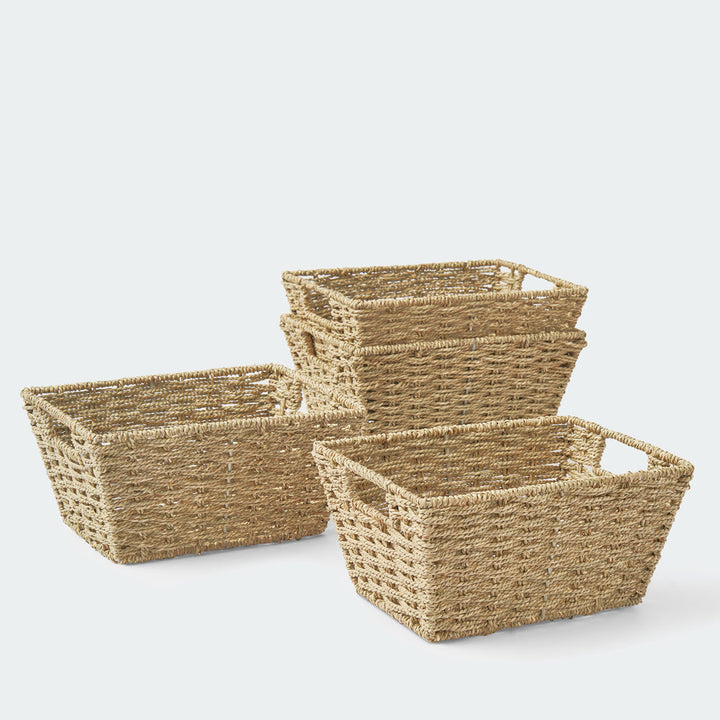 A twisted seagrass wicker storage basket filled with bathroom towels on a wooden table