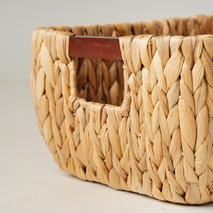 A close-up look at a wooden handle of a rectangle arrow water hyacinth wicker storage basket