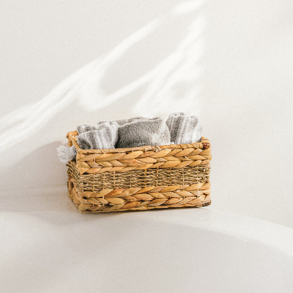 A rectangle mixed seagrass and water hyacinth wicker storage basket filled with towels